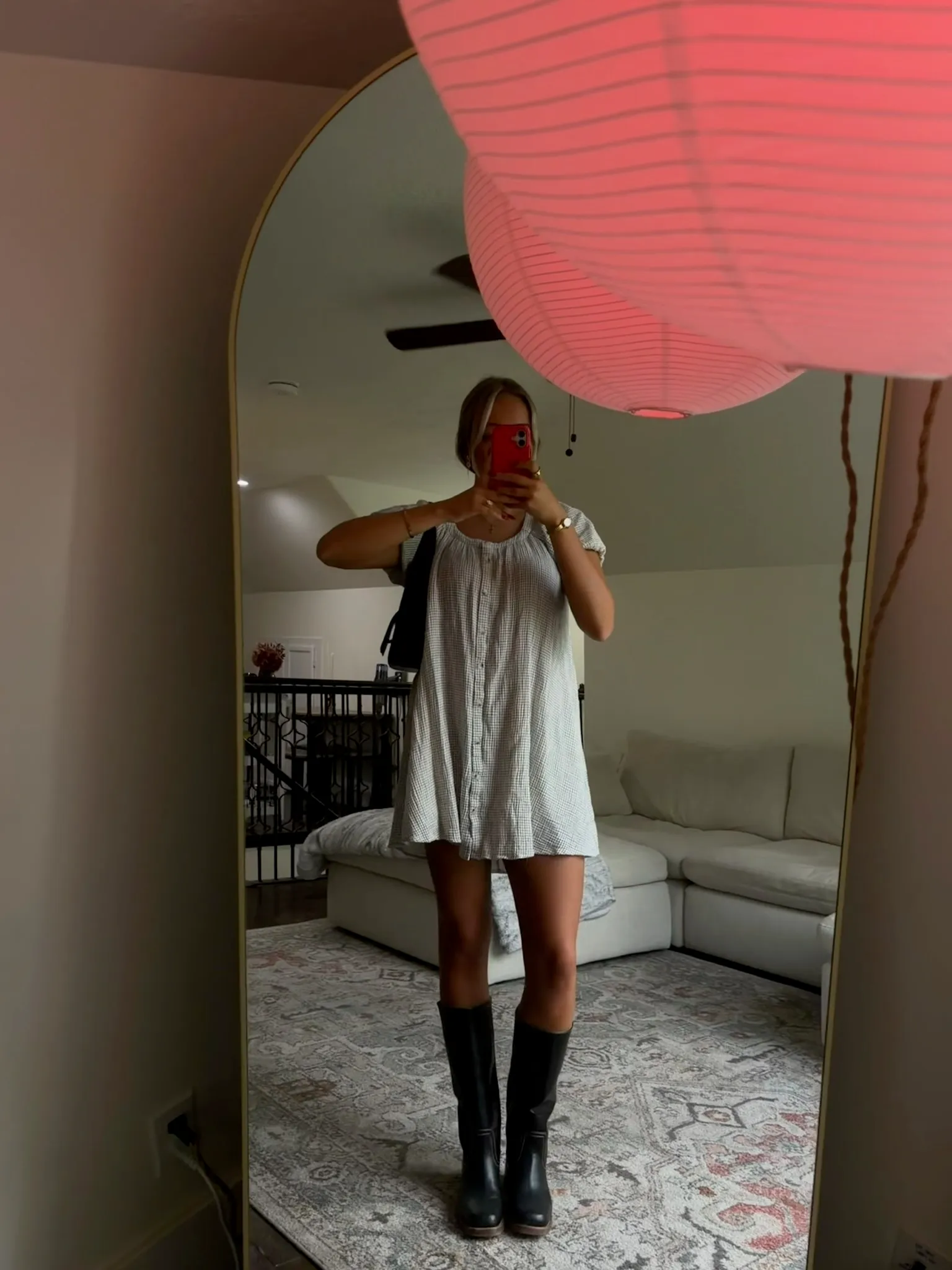 Client in a mini dress and boots showing off her spray tan in a mirror selfie