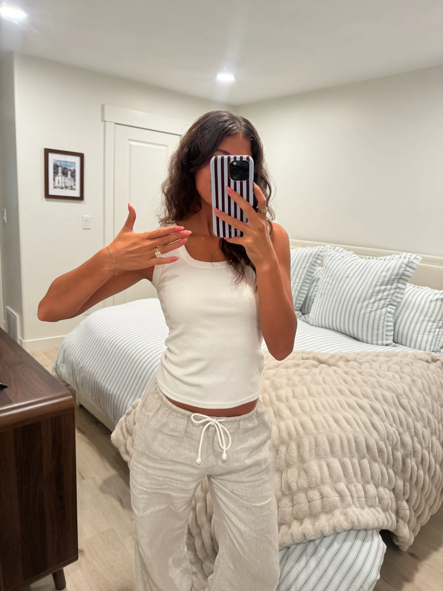 Client in a white tank top showing off her golden spray tan in a mirror selfie